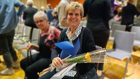 Eine Frau hält eine Blume und eine kleine Windmühle in der Hand.