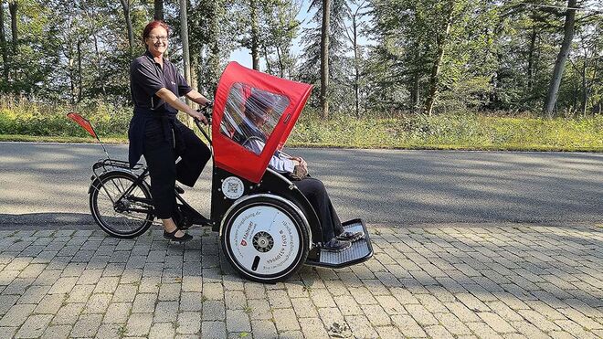 Eine Frau sitzt auf dem Fahrersitz der Malteser-Rikscha.