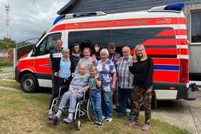 Die Familie steht für ein Gruppenfoto vor dem Herzenswunsch-Krankenwagen.